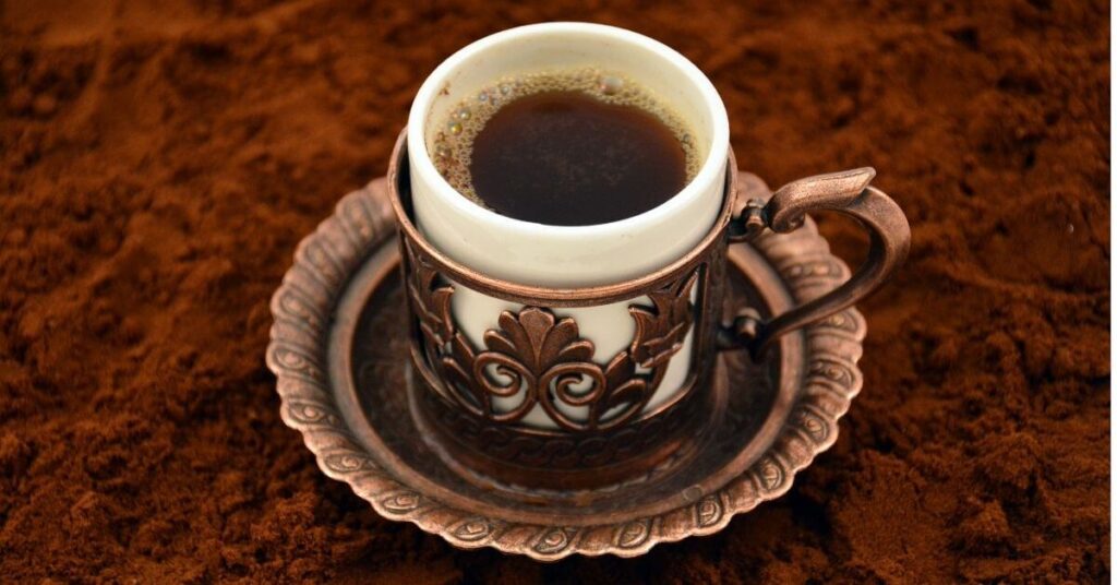 White Turkish coffee cup on top of coffee ground 
